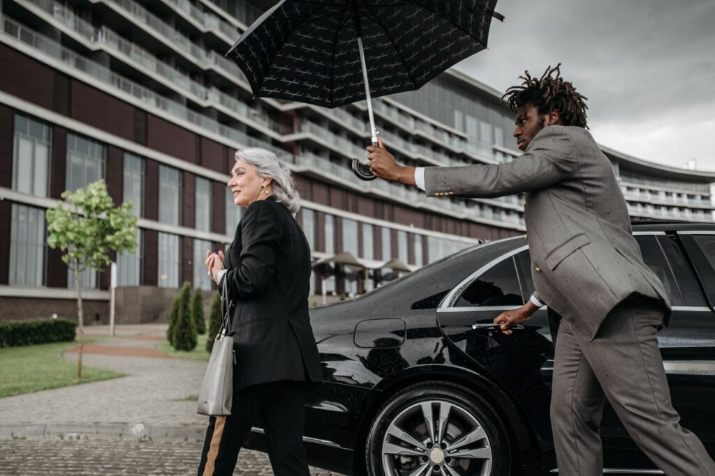 The Art of Drawing Readers In: Your attractive post title goes here A business professional holds an umbrella for a colleague as they exit a luxury car in front of an office building.